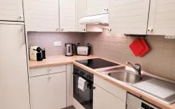 Bild 11: Eine voll ausgestattete Küche mit Waschmaschine, Backofen, Herd, Nespresso-Kaffeemaschine und Milchschäumer.